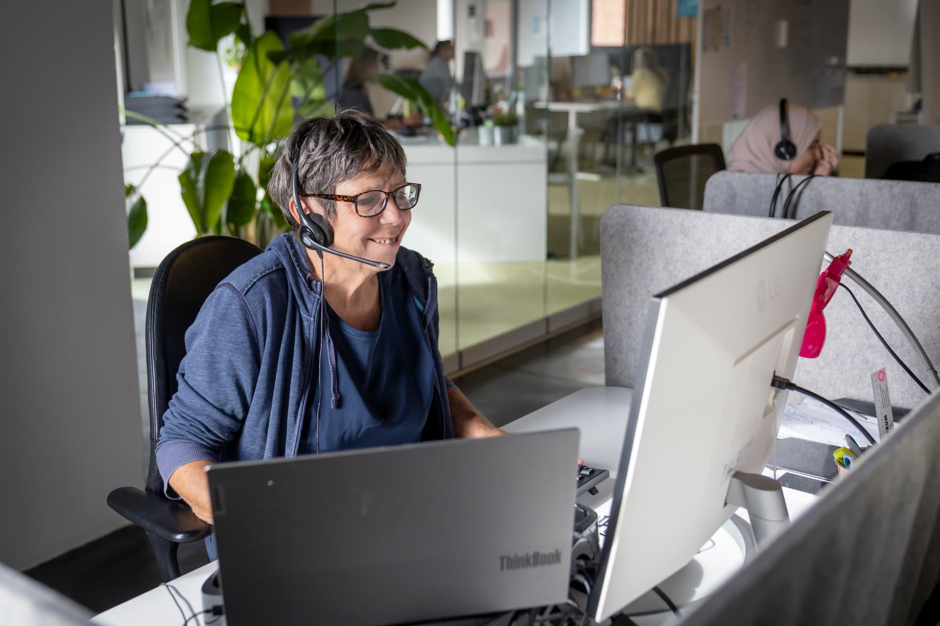 Agente met headset luistert glimlachend naar een beller